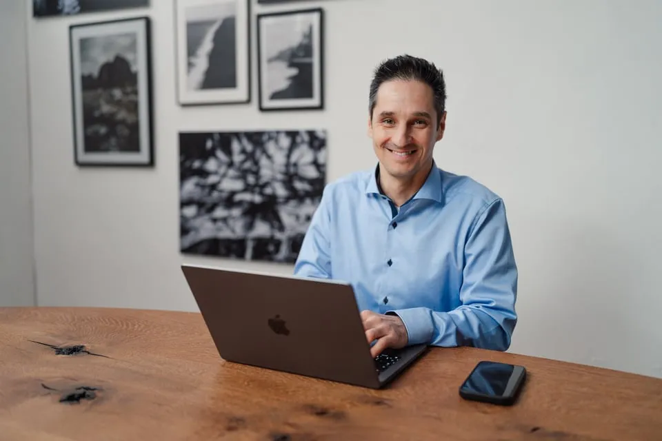 Alex Pippir sitzt lächelnd am Laptop