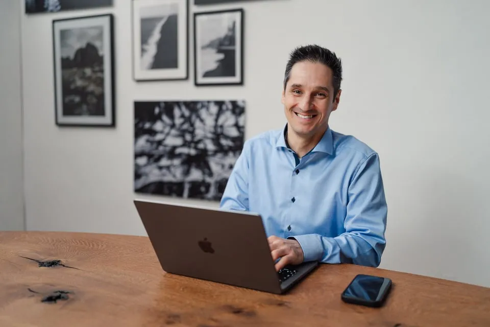 Alex Pippir sitzt lächelnd am Laptop