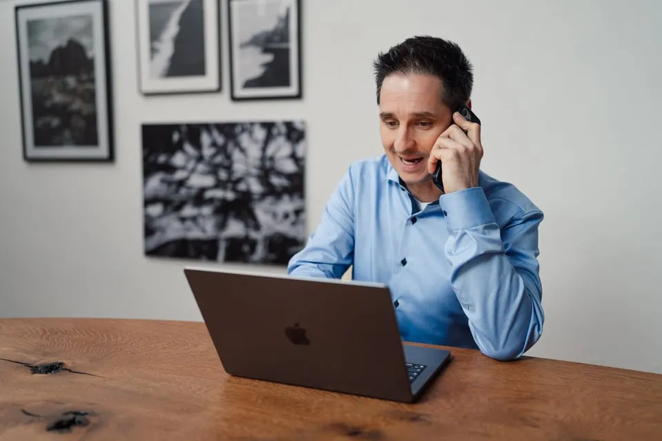 Alex Pippir telefoniert lächelnd am Laptop