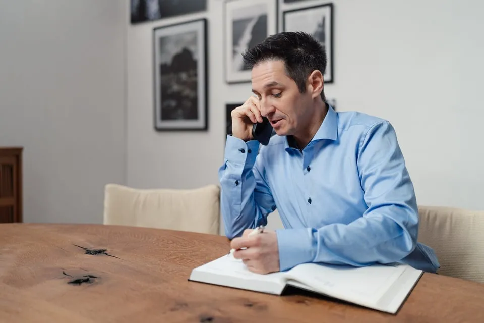 Alex Pippir telefoniert und schreibt sich Notizen in ein Buch