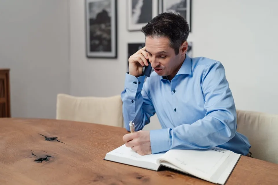 Alex Pippir telefoniert und macht sich Notizen in einem Buch