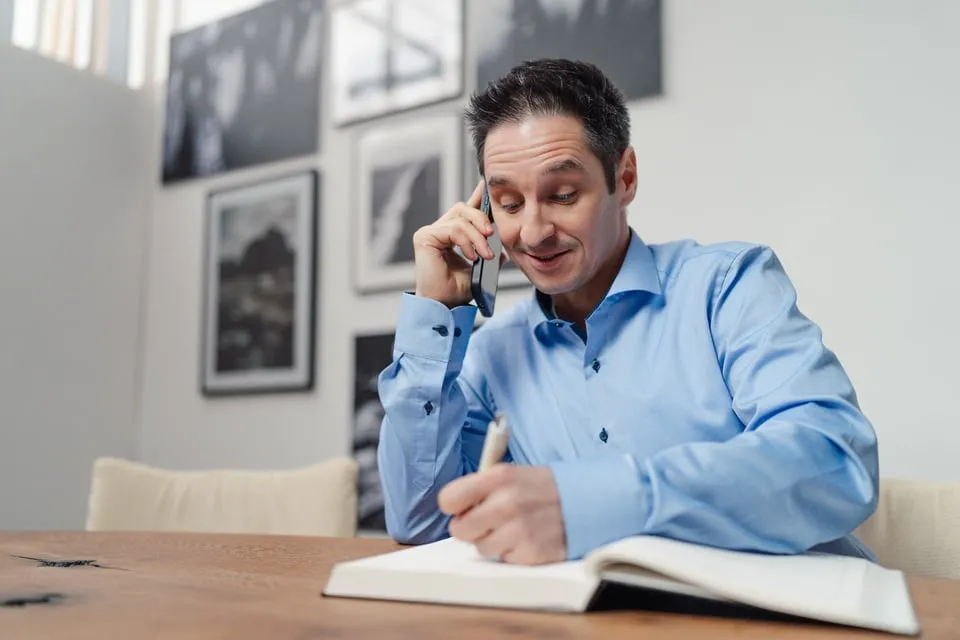 Alex Pippir telefoniert und schreibt Notizen in ein Buch